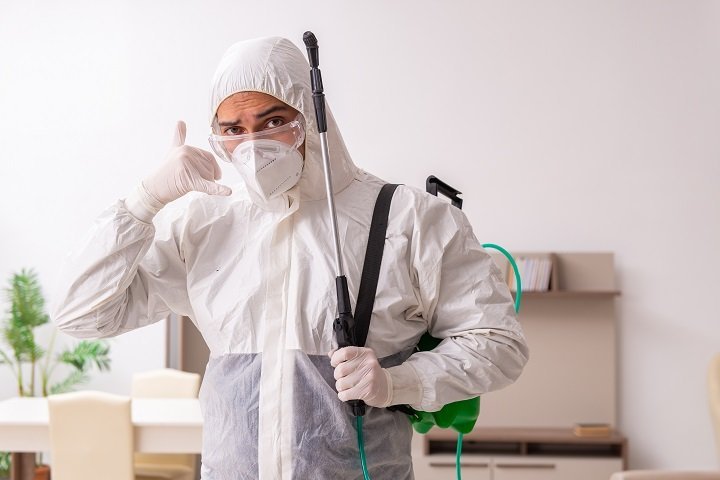 exterminator in a white suit gesturing to call him