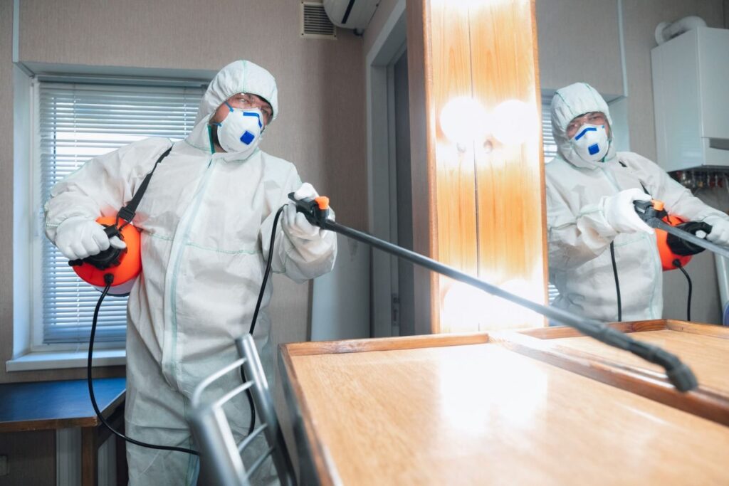 man spraying desk for bugs